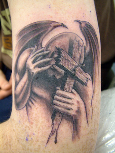 devil-with-cross-in-hand-grey-ink-tattoo-on-bicep.jpg